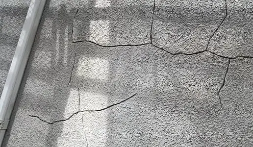 モルタル外壁に大きなひび割れが複数見られる状態の写真