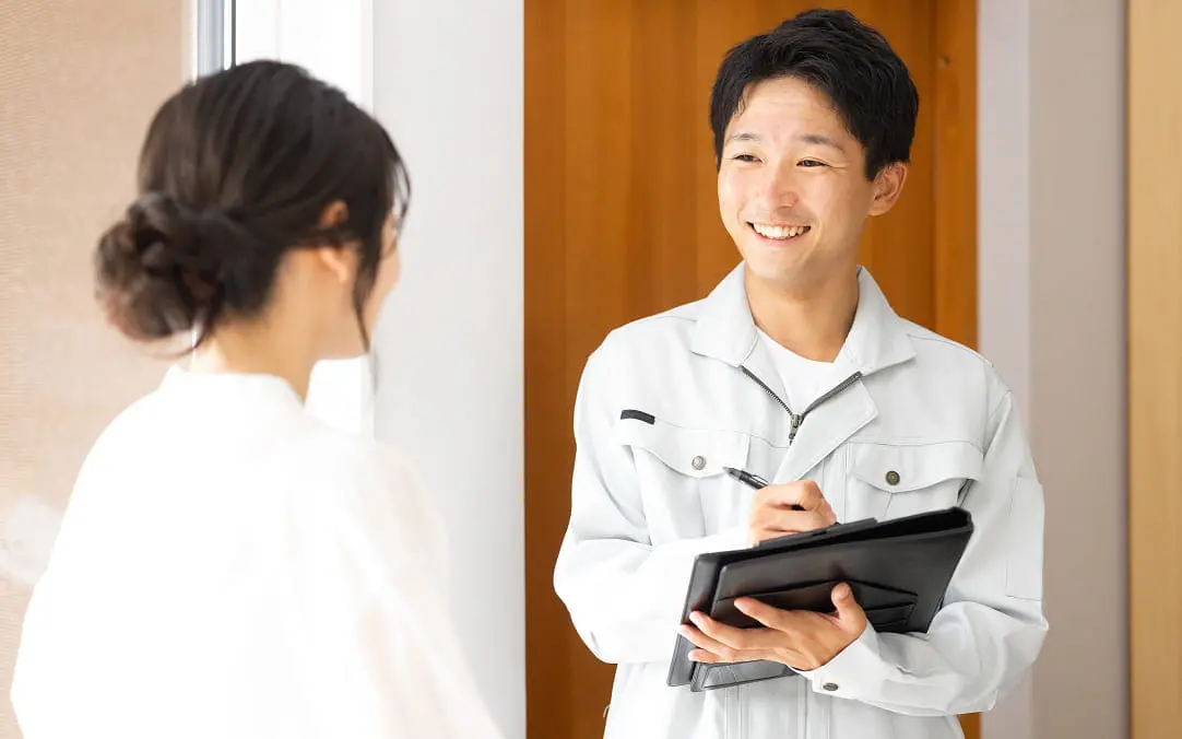 作業服の男性がタブレットを持って女性と笑顔で会話する様子