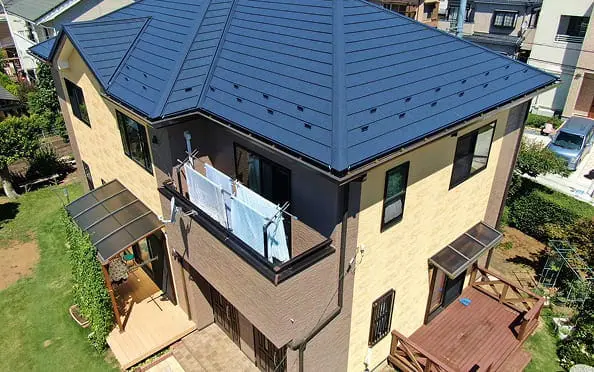 青い屋根とベランダが特徴的な2階建て住宅を上空から撮影した写真
