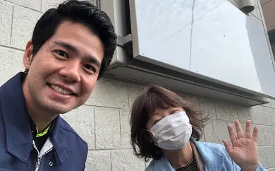 白い壁の前で若い男性とマスク姿の女性が並んで撮影