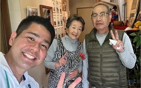 室内で年配の夫婦と若い男性が笑顔で写る記念写真