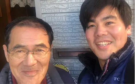 年配男性と若い男性が玄関前で笑顔を見せているツーショット