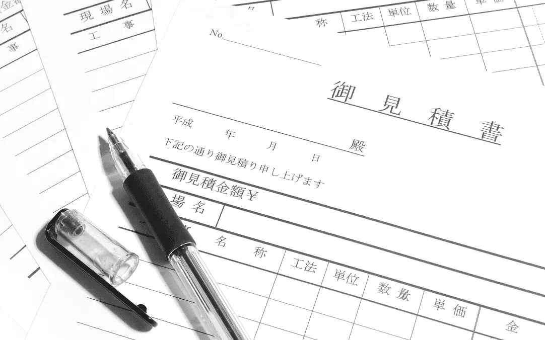 見積書とペンが置かれた白黒写真で、工事や金額記入欄が見える書類の構図
