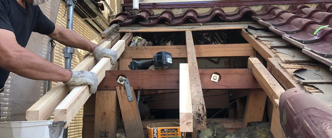 作業員が木材を準備している姿と露出した断熱材が見える