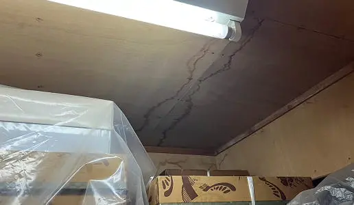 天井の下には段ボール箱が積まれ、ビニールで覆われた物品が保管されている