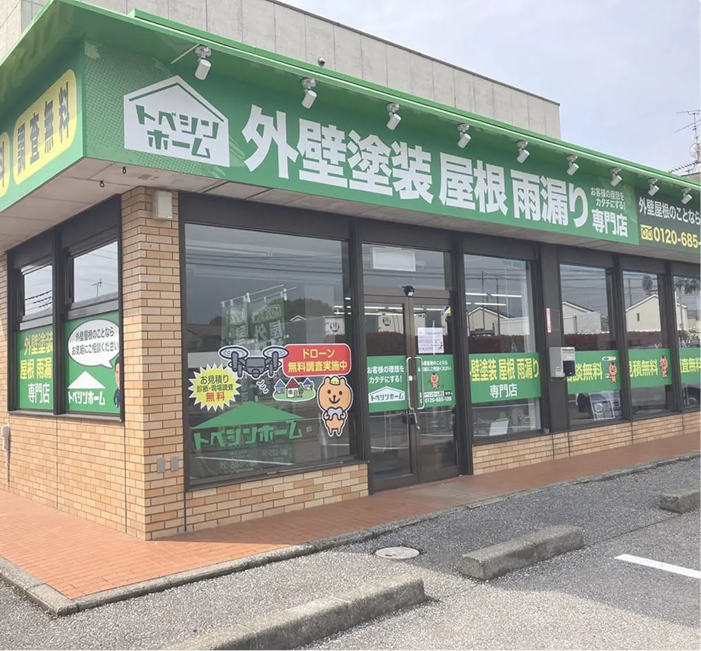 「トベシンホーム 外壁塗装 屋根 雨漏り専門店」と掲示された緑の看板の店舗